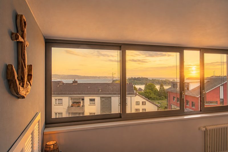 Blick aus dem Basic-Zimmer über die Dächer auf den See im Abendlicht