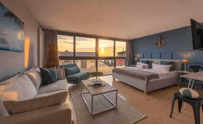 Family-and-Friends-Zimmer mit Sofa, Doppelbett und Panoramafront im Sonnenuntergang